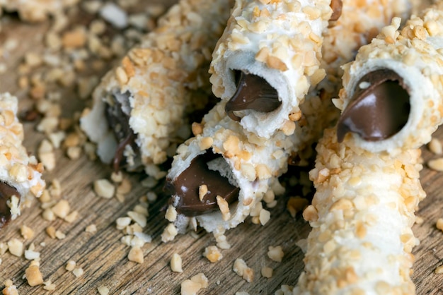 Waffelröhrchen mit Schokoladenfüllung und zerkleinerten Erdnüssen