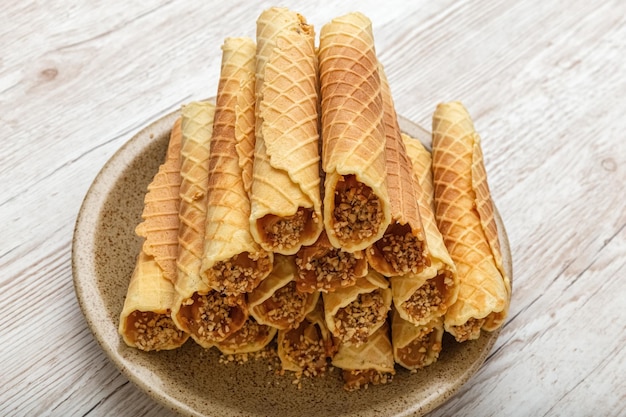 Waffelröllchen mit Sahne auf einem Teller. Leckeres Dessert. Hausgemacht. Hölzerner Hintergrund. Foto