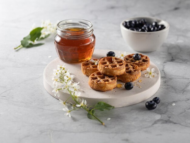 Waffels belgas caseiros com mirtilo e mel na mesa de mármore Vertical