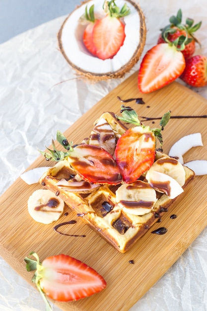 Waffle belga com molho de frutas e chocolate é lindamente servido em uma placa de madeira