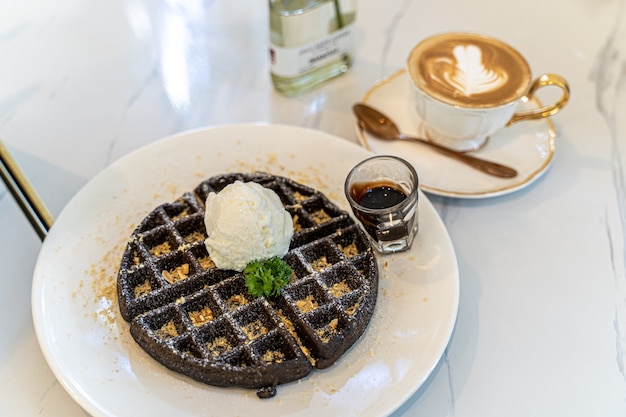 Waffle de chocolate con cobertura de helado de vainilla sirve con café caliente