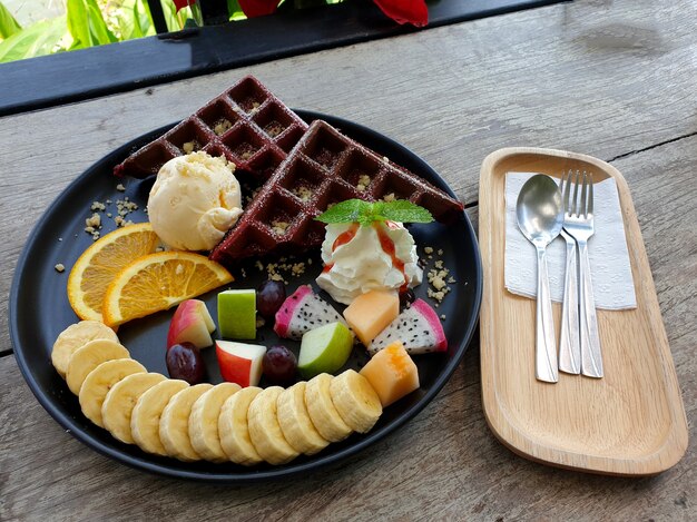 Waffle de banana, maçã, laranja e fruta do dragão com sorvete de baunilha, sobremesa