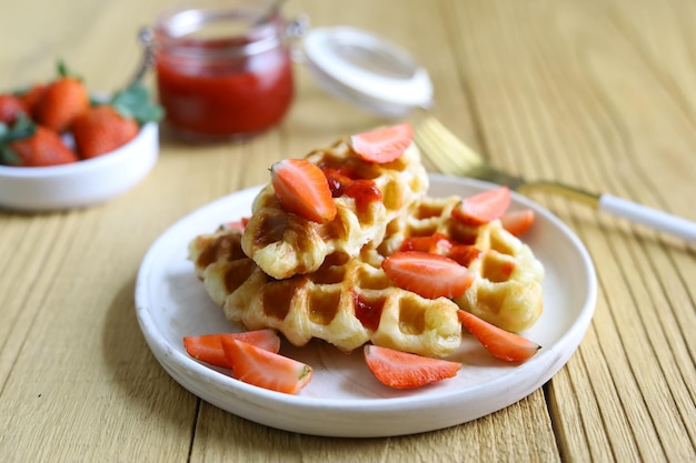 Waffle de croissant ou croffel em chapa branca com geléia de morango com fundo de madeira