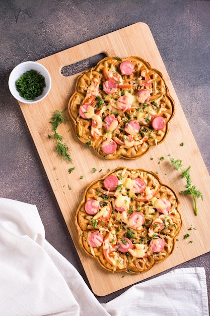 Waffle de pizza apetitosa com salsichas de legumes e queijo em uma placa vista superior e vertical