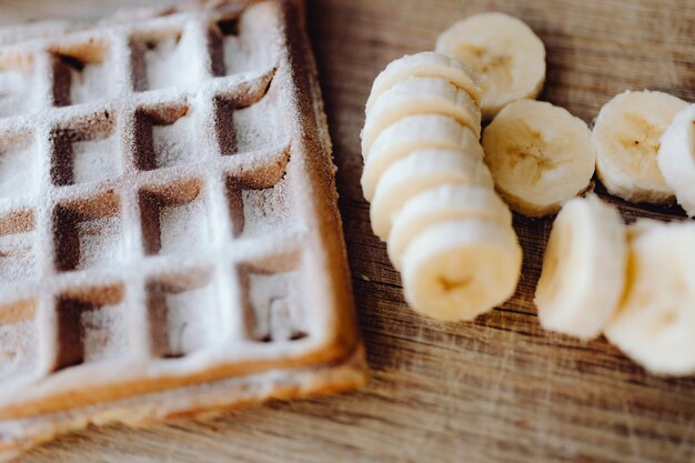 Waffle y rodajas de banana en una bandeja de madera