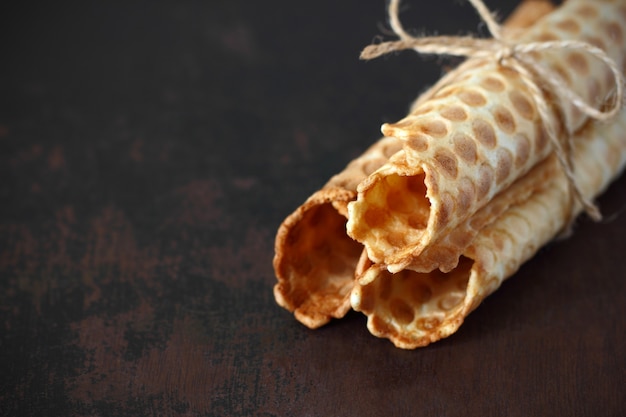 Foto waffle rollos atados con una cuerda sobre una mesa oscura.