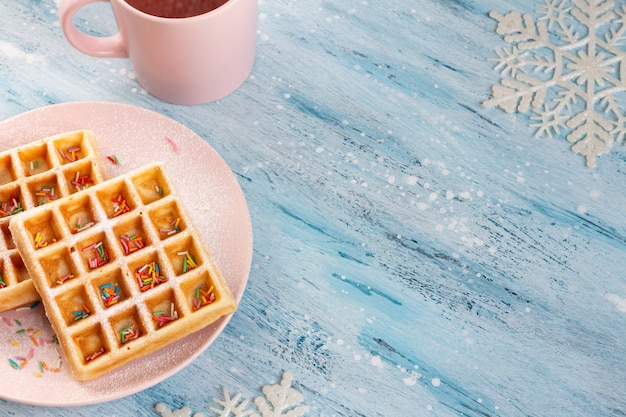 Waffles belgas con azúcar en polvo y confites de confitería en el plato