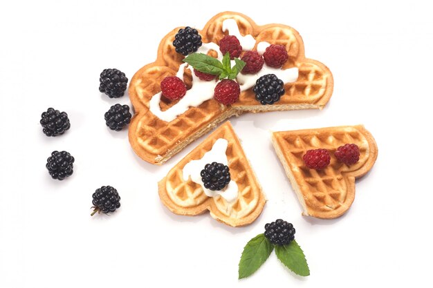 Waffles belgas con bayas frescas aisladas sobre fondo blanco