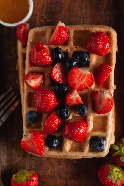 Foto waffles belgas caseros frescos en una vieja mesa de madera con frambuesas arándanos y miel