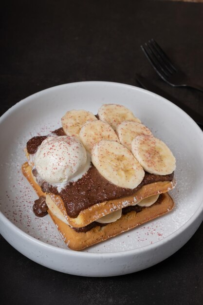 Foto waffles belgas com bananas e molho de chocolate com vista de ângulo de sorvete