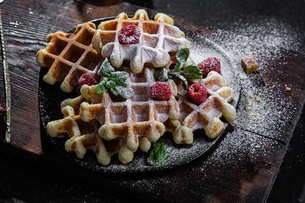 Waffles belgas com framboesas e hortelã num prato escuro