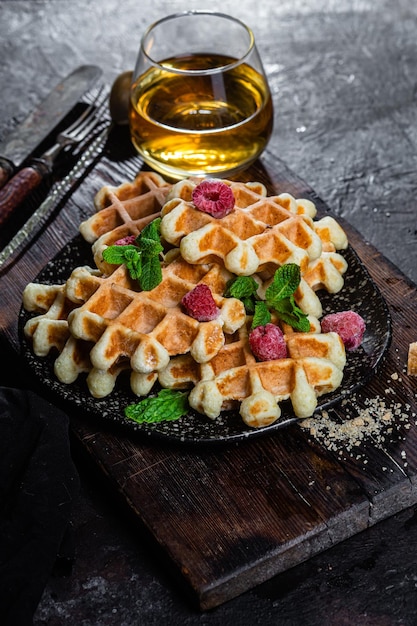 Waffles belgas com framboesas e hortelã num prato escuro