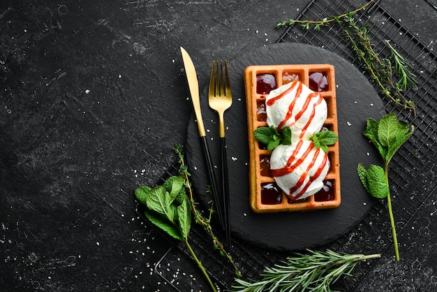 Waffles belgas com geléia de morango e hortelã sobremesa em uma placa de pedra preta