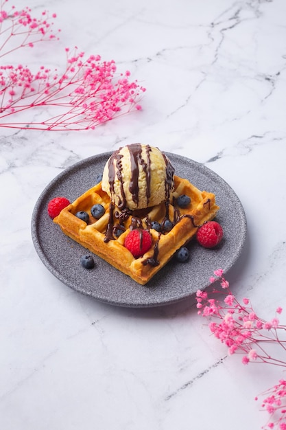 Waffles belgas com sorvete de frutas e flor em verde foto de alta qualidade