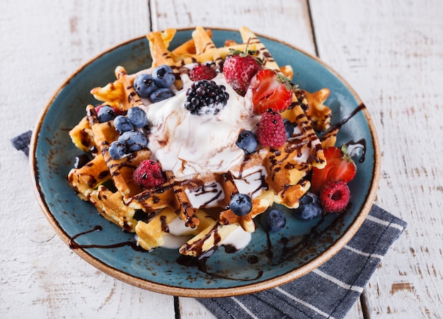 Waffles belgas com sorvete, frutas frescas e molho de chocolate.