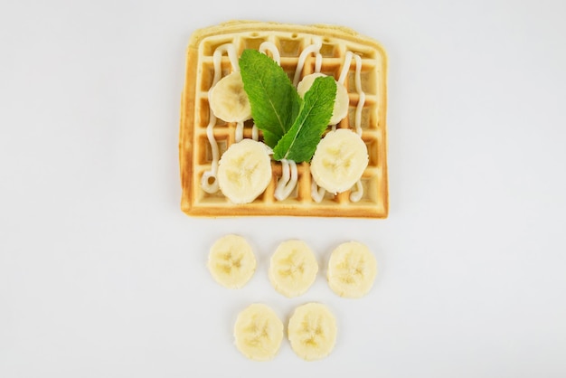 Waffles belgas cuadrados con plátano y leche condensada sobre un fondo blanco Waffles deliciosos y dulces vista desde arriba