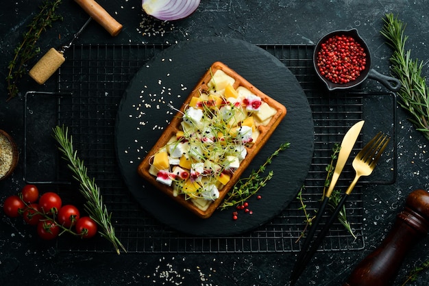 Waffles belgas de café da manhã com queijo brie feta e parmesão Em uma placa de pedra preta