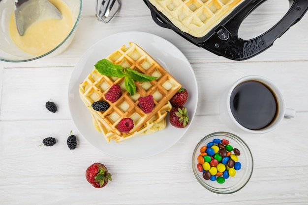 Waffles belgas con diferentes bayas en blancoWaffles dulces en un plato blanco