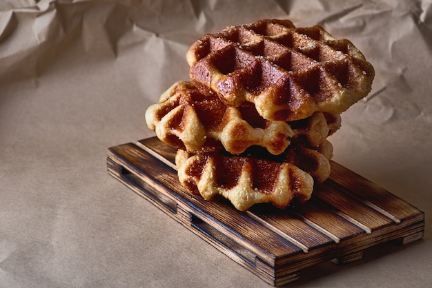 Waffles belgas em papel pardo e bandeja de madeira