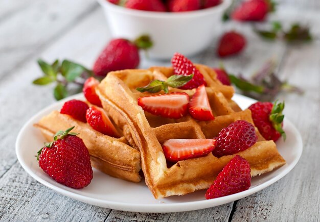 Waffles belgas con fresas y menta en un plato blanco