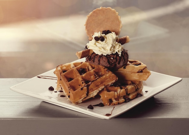 Foto waffles belgas con helado y chocolate en plato blanco sobre la mesa en un café