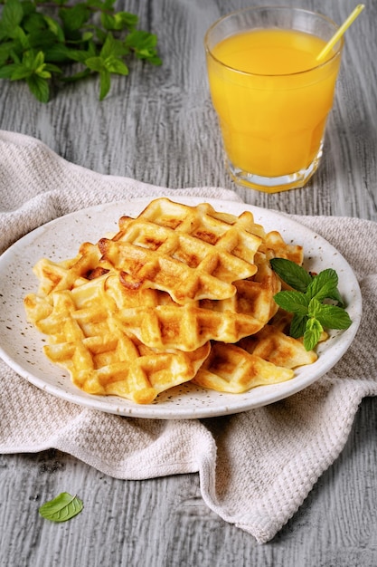 Waffles belgas y jugo de naranja sobre un fondo gris