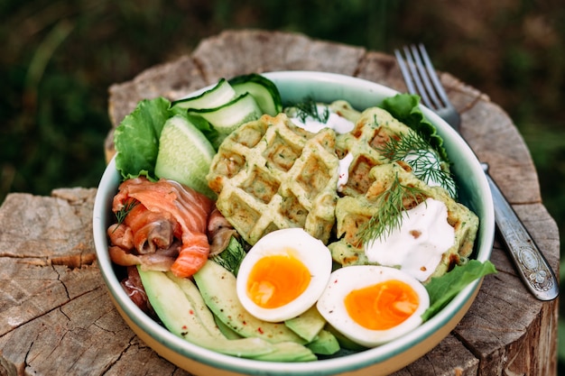 Waffles belgas con salmón, aguacate y huevo en un plato