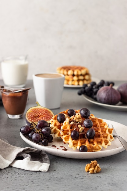 Waffles belgas tradicionais com molho de caramelo, uvas e figos. café da manhã aconchegante de outono ou inverno.
