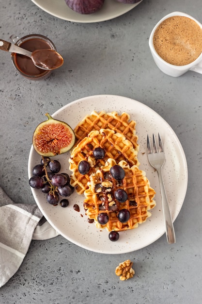 Waffles belgas tradicionais com molho de caramelo, uvas e figos. Café da manhã aconchegante de outono ou inverno.