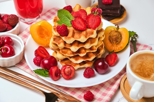 Waffles belgas tradicionales horneados caseros con bayas y una taza de café, el enfoque selectivo