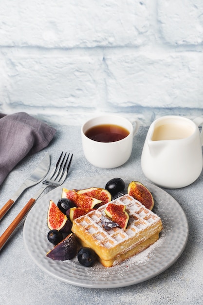 Waffles belgas tradicionales con uvas de azúcar en polvo e higos