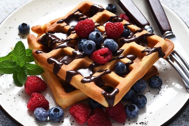 Waffles belgas de vainilla con frutos rojos y una taza de café para el desayuno.