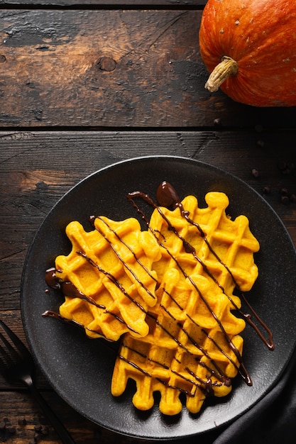 Waffles de calabaza con chocolate y azúcar en polvo sobre fondo oscuro