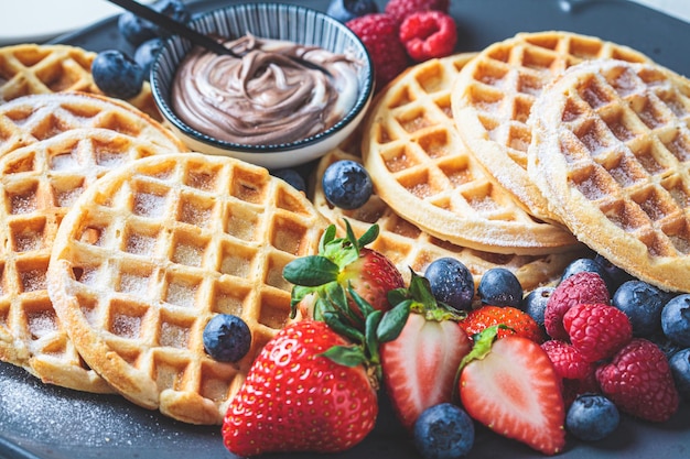 Waffles caseiros com frutas e creme de chocolate no fundo cinza da placa escura conceito de café da manhã familiar