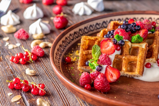 Waffles caseiros com molho de berry e queijo creme em um prato sobre uma mesa de madeira