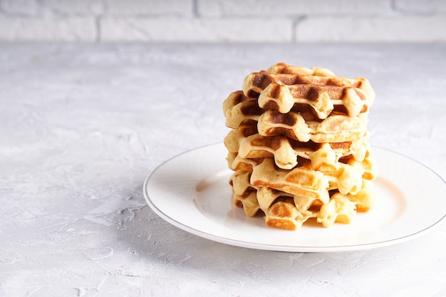 Waffles caseiros deliciosos servidos em chapa branca sobre uma mesa branca