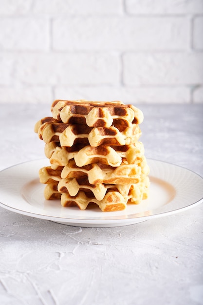 Waffles caseiros deliciosos servidos em chapa branca sobre uma mesa branca