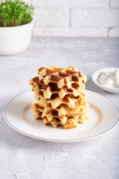 Waffles caseiros deliciosos servidos em chapa branca sobre uma mesa branca