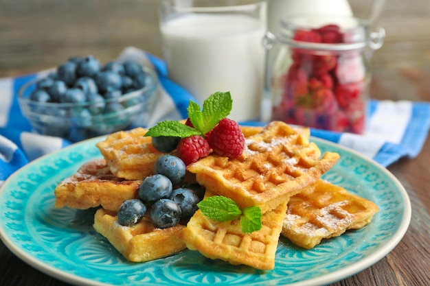 Waffles caseiros doces com frutas da floresta e molho no fundo da mesa