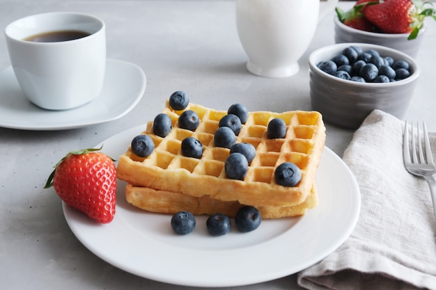 Waffles caseiros vienenses ou belgas frescos com mirtilos e morangos em um prato branco