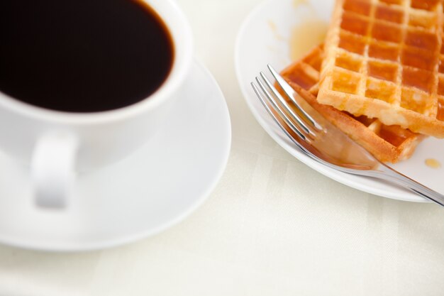Waffles colocados junto a una taza de café