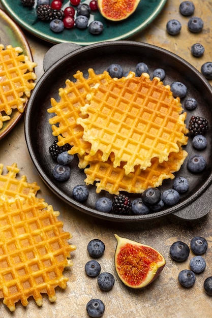 Waffles crocantes e frutas vermelhas em uma frigideira Meio figo, mirtilos e waffles