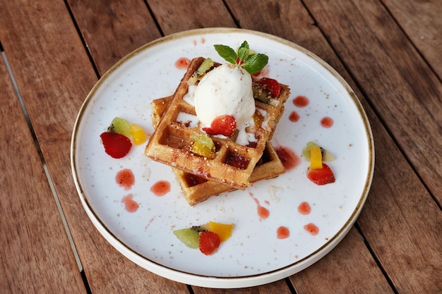 Waffles da Bélgica com frutas e sorvete Servido com prato na mesa de madeira Imagem de foco seletivo