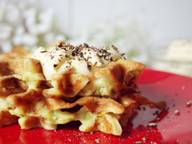 Waffles de abobrinha num prato vermelho com molho e especiarias