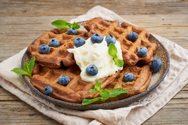 Waffles de banana de chocolate com mirtilos, na mesa de madeira velha escura. vista lateral