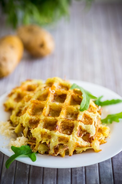 Waffles de batata frita com queijo em um prato na mesa de madeira