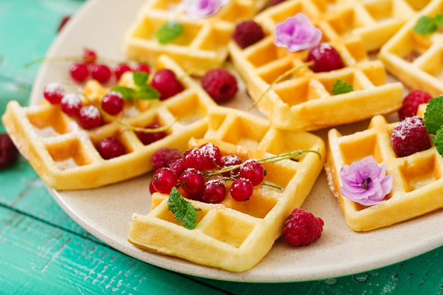 Waffles de Bélgica com framboesas e iogurte no prato.