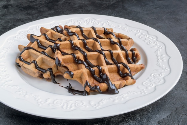 Foto waffles de chocolate belgas com calda de chocolate.