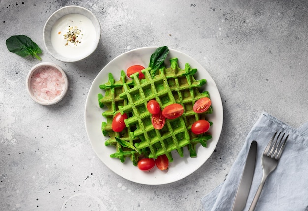 Waffles de espinafre verde na mesa com toalha de linho e talheres