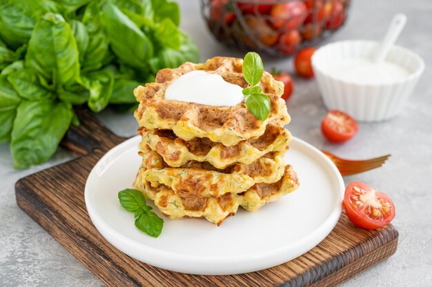 Waffles de queijo de abobrinha caseiro com creme de leite e manjericão fresco em um prato de
